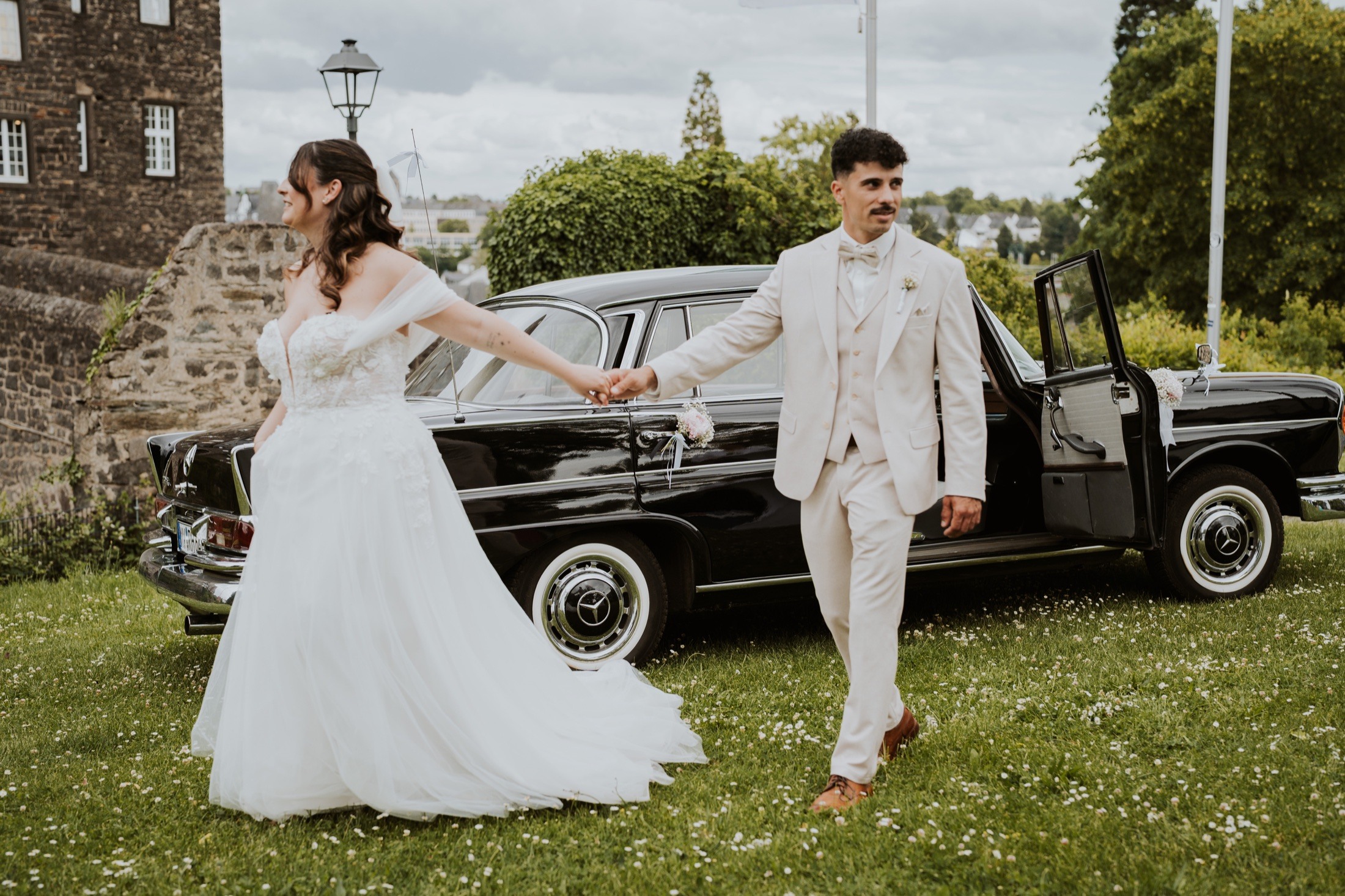 A wedding couple in front of their classic wedding car.