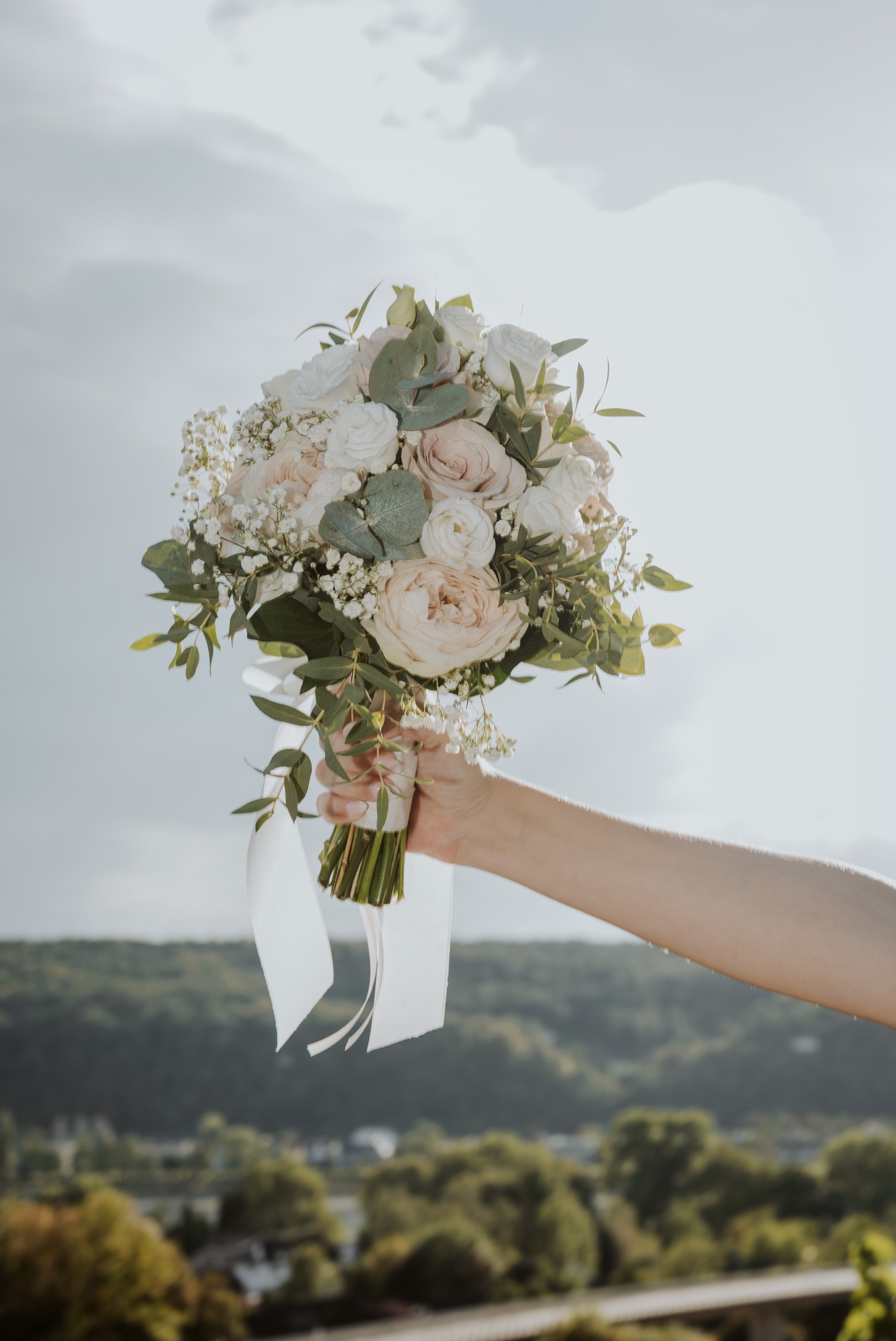 Lea’s bouquet of roses and eucalyptus beneath an open sky.