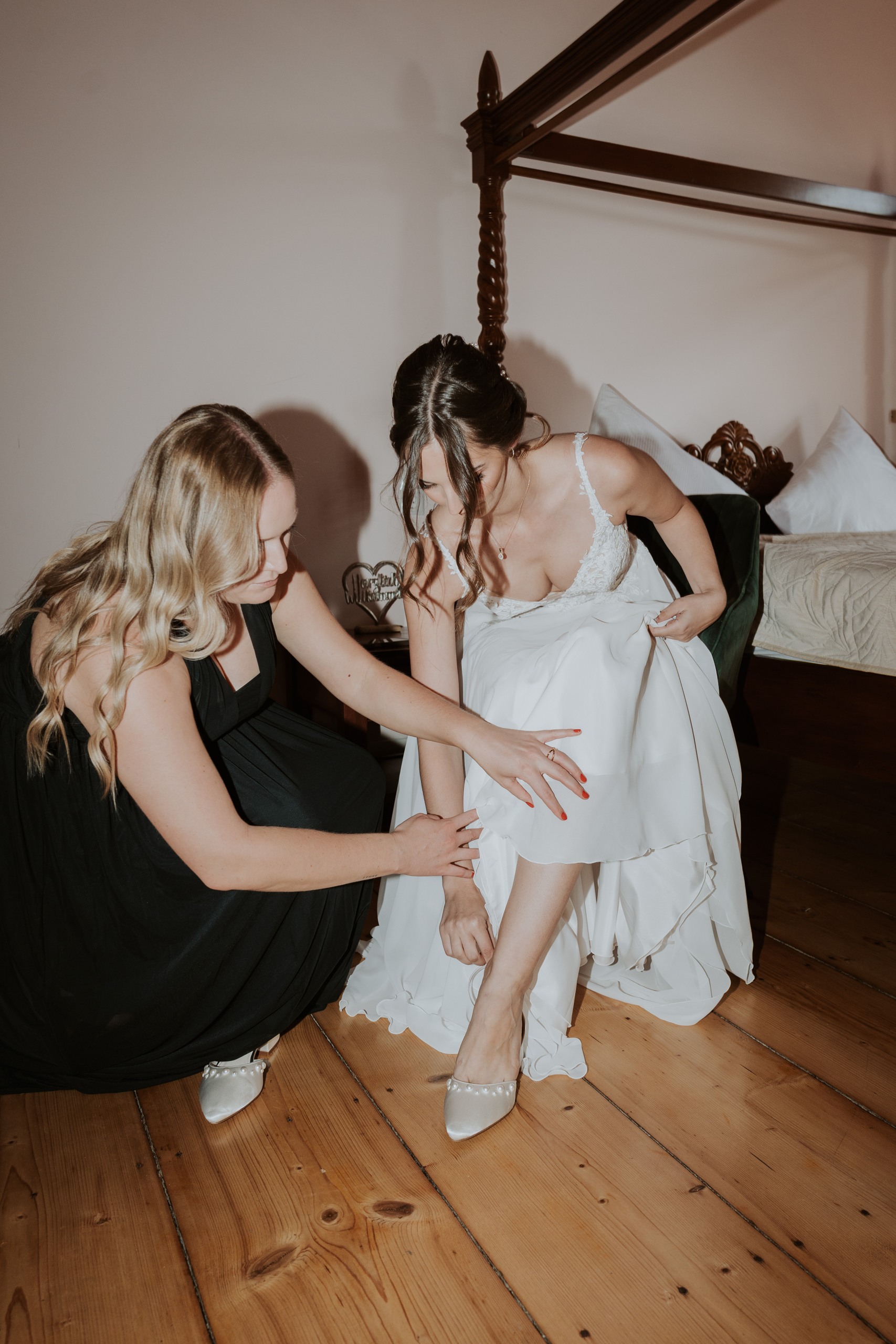 Lea bekommt beim Anziehen ihrer Brautschuhe Unterstützung.
