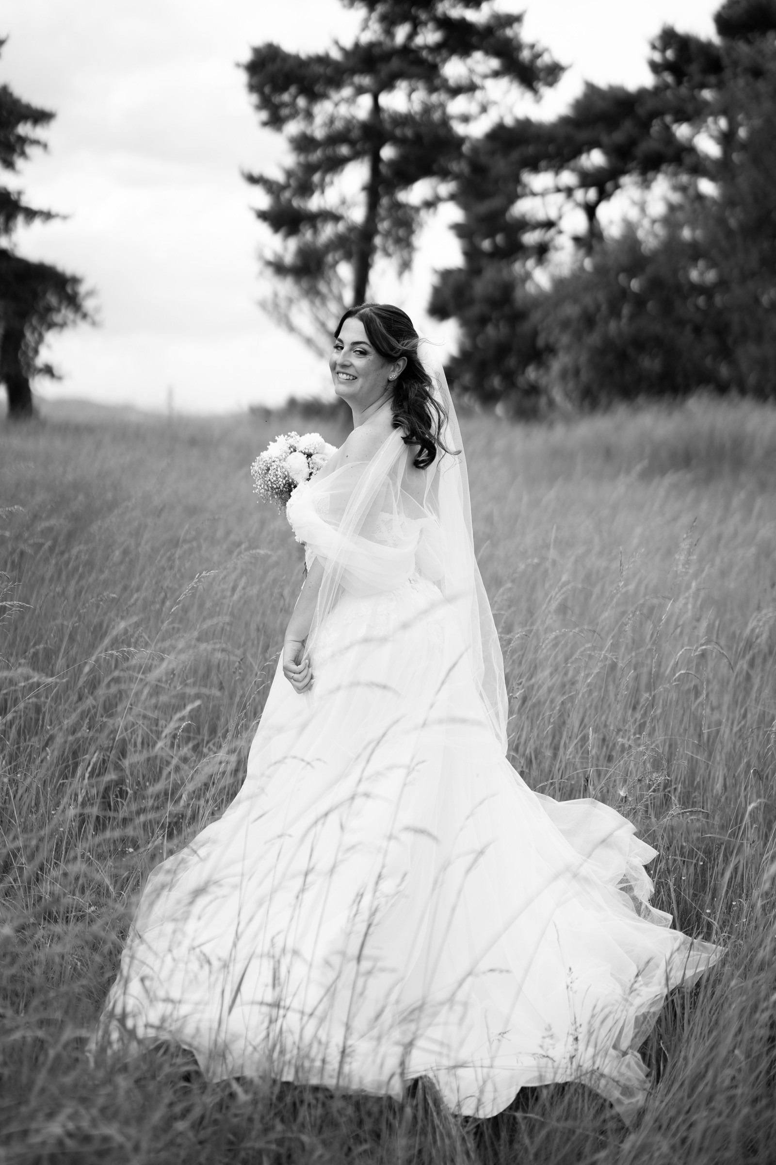 A bride with her veil in a meadow.