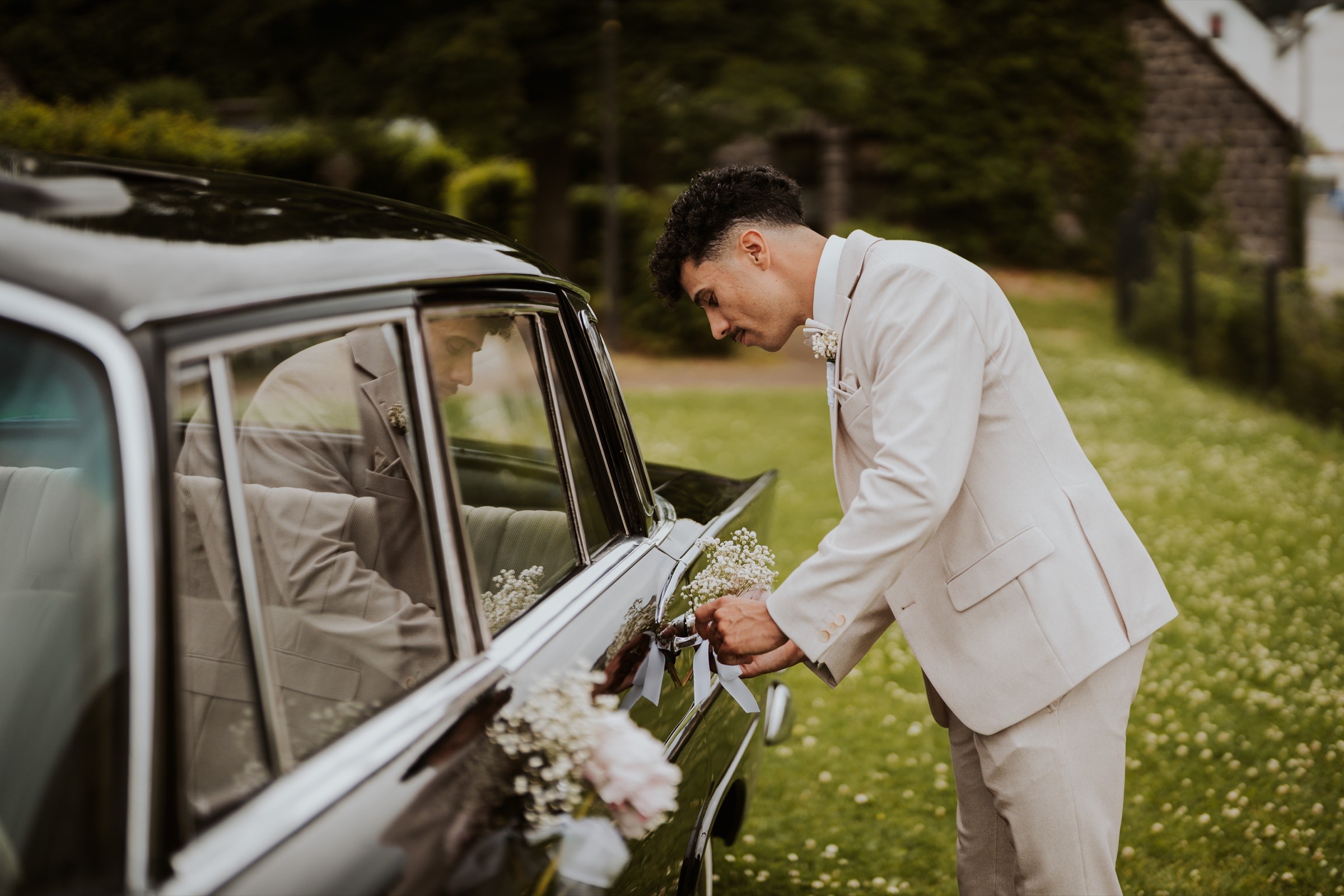 The groom opening the wedding car door.
