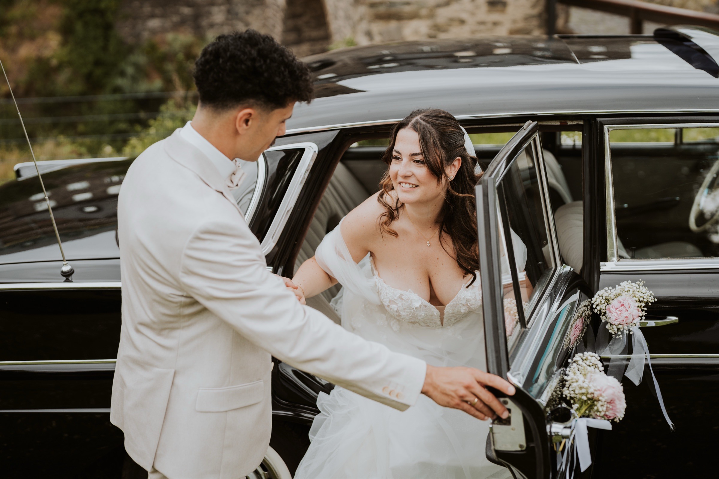 A wedding couple beside their car.